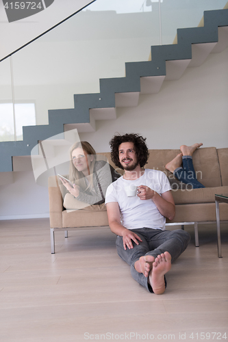 Image of couple relaxing at  home with tablet computers