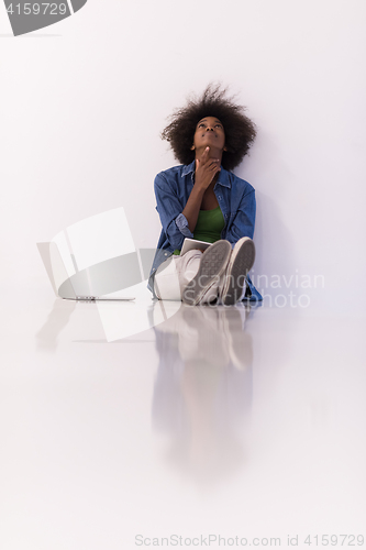 Image of african american woman sitting on floor with laptop