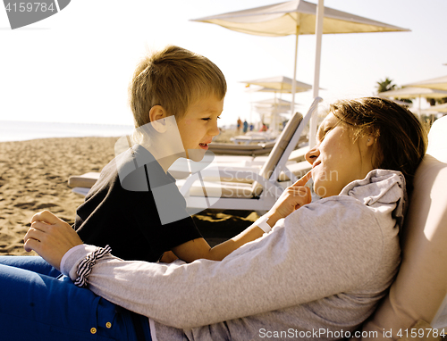 Image of young mother with son resting on sea coast, happy family togethe