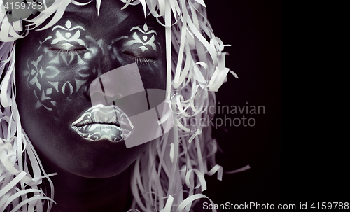 Image of creative make up like Ethiopian mask, white pattern on black face close up