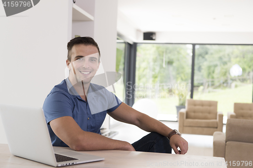Image of Young man with laptop at home