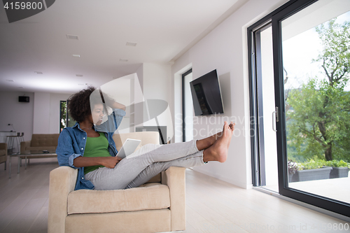 Image of african american woman at home with digital tablet