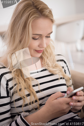 Image of woman sitting on sofa with mobile phone