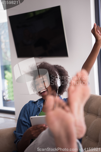 Image of African american woman at home in chair with tablet and head pho