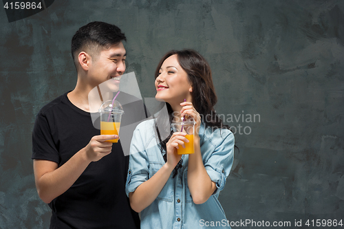 Image of A young pretty Asian couple with a glasses of Orange juice