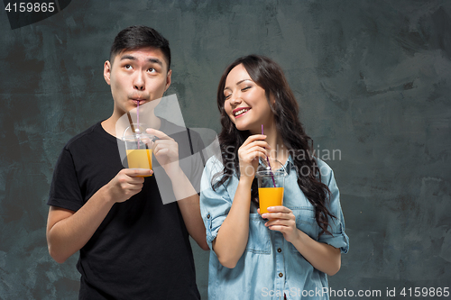 Image of A young pretty Asian couple with a glasses of Orange juice