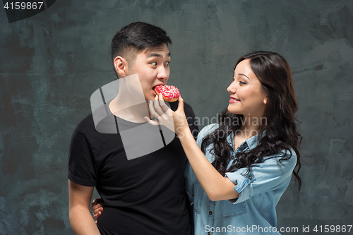 Image of Young asian couple enjoy eating of sweet colorful donut