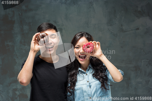 Image of Young asian couple enjoy eating of sweet colorful donut