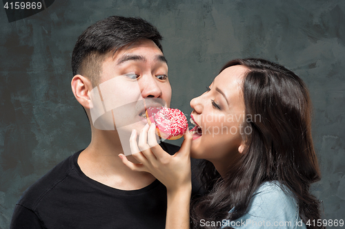 Image of Young asian couple enjoy eating of sweet colorful donut