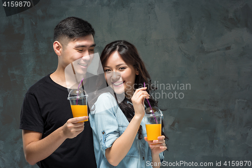 Image of A young pretty Asian couple with a glasses of Orange juice