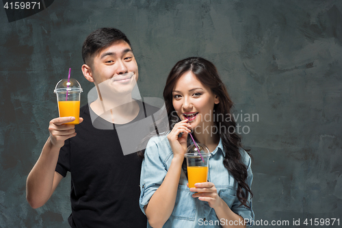 Image of A young pretty Asian couple with a glasses of Orange juice