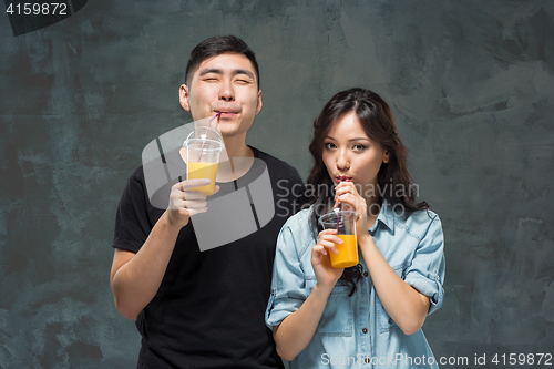 Image of A young pretty Asian couple with a glasses of Orange juice