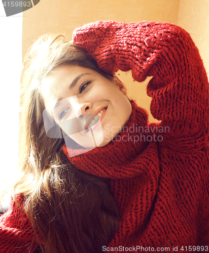 Image of young pretty real woman in sweater and scarf all over her face smiling