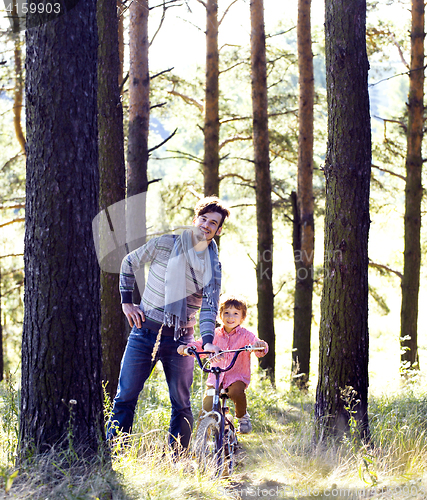 Image of father learning his son to ride on bicycle outside