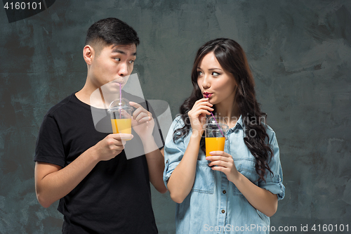 Image of A young pretty Asian couple with a glasses of Orange juice