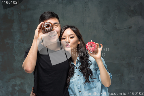 Image of Young asian couple enjoy eating of sweet colorful donut