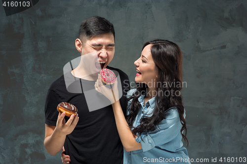 Image of Young asian couple enjoy eating of sweet colorful donut