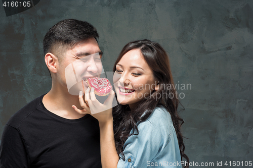 Image of Young asian couple enjoy eating of sweet colorful donut