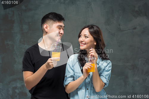 Image of A young pretty Asian couple with a glasses of Orange juice