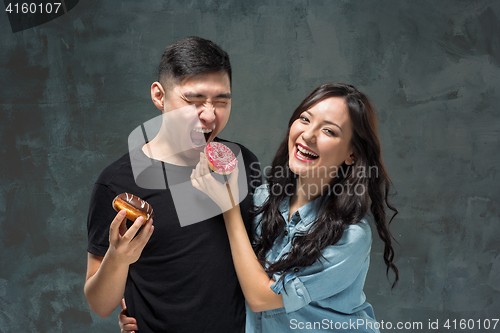 Image of Young asian couple enjoy eating of sweet colorful donut