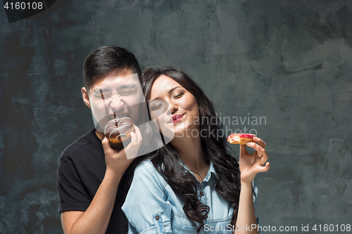 Image of Young asian couple enjoy eating of sweet colorful donut