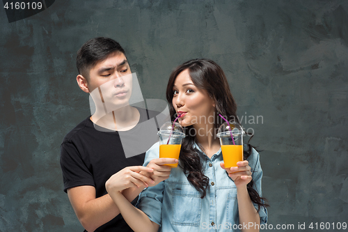 Image of A young pretty Asian couple with a glasses of Orange juice