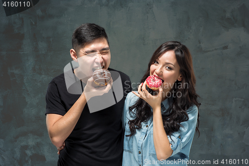 Image of Young asian couple enjoy eating of sweet colorful donut