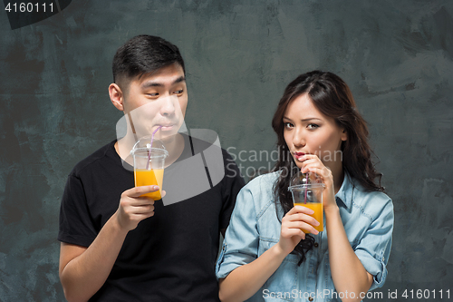 Image of A young pretty Asian couple with a glasses of Orange juice