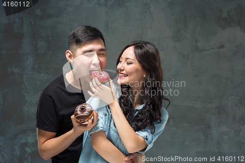 Image of Young asian couple enjoy eating of sweet colorful donut