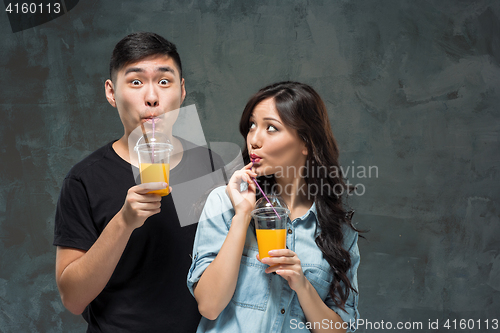 Image of A young pretty Asian couple with a glasses of Orange juice