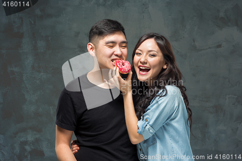 Image of Young asian couple enjoy eating of sweet colorful donut