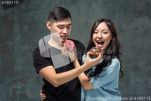 Image of Young asian couple enjoy eating of sweet colorful donut