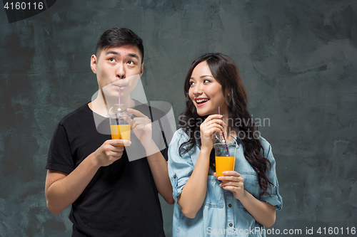 Image of A young pretty Asian couple with a glasses of Orange juice