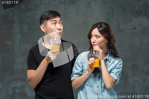 Image of A young pretty Asian couple with a glasses of Orange juice