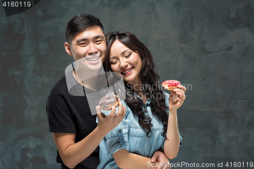 Image of Young asian couple enjoy eating of sweet colorful donut