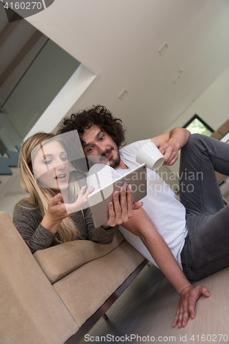Image of couple relaxing at  home with tablet computers