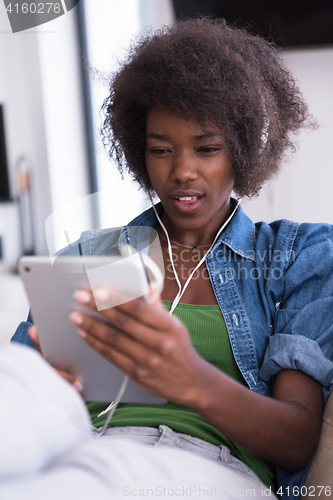 Image of African american woman at home in chair with tablet and head pho