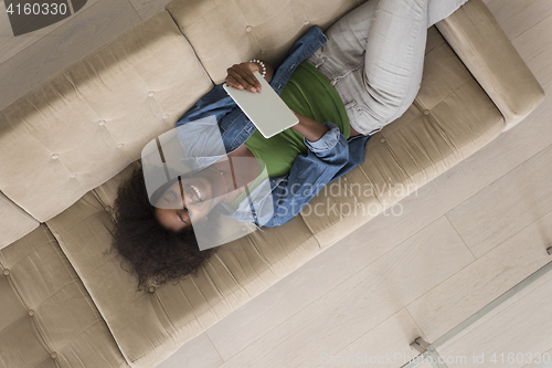 Image of african american woman at home with digital tablet top view