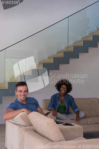 Image of multiethnic couple relaxing at  home with tablet computers