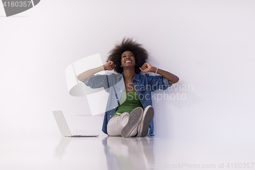 Image of african american woman sitting on floor with laptop