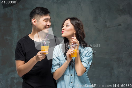 Image of A young pretty Asian couple with a glasses of Orange juice