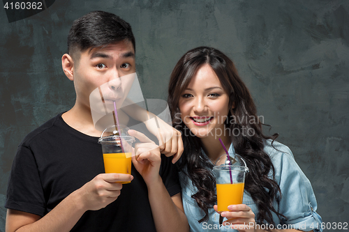 Image of A young pretty Asian couple with a glasses of Orange juice