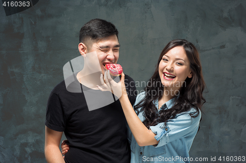 Image of Young asian couple enjoy eating of sweet colorful donut