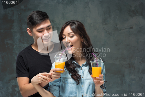 Image of A young pretty Asian couple with a glasses of Orange juice