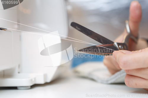 Image of Seamstress cuts with scissors thread