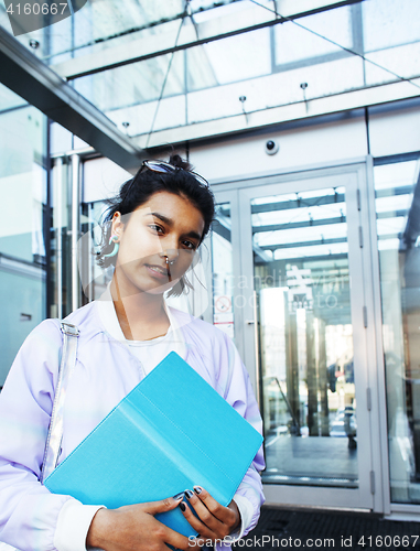 Image of young cute modern indian girl at university building sitting on 