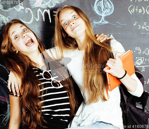 Image of back to school after summer vacations, two teen real girls in classroom with blackboard painted together, lifestyle real people concept