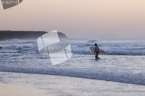Image of Surfers on beach with surfboard.