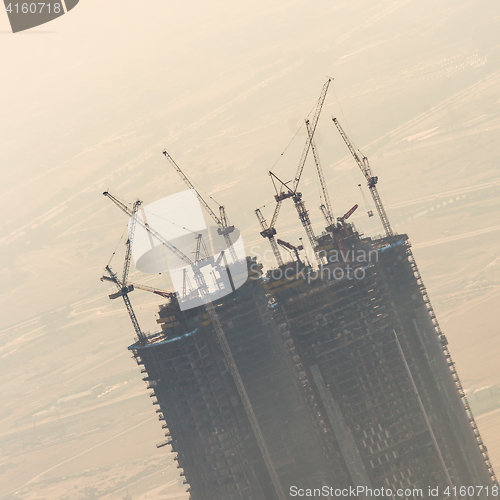 Image of Skyscraper construction site with cranes on top of buildings.