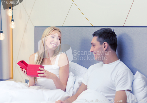 Image of smiling couple in bed with red gift box